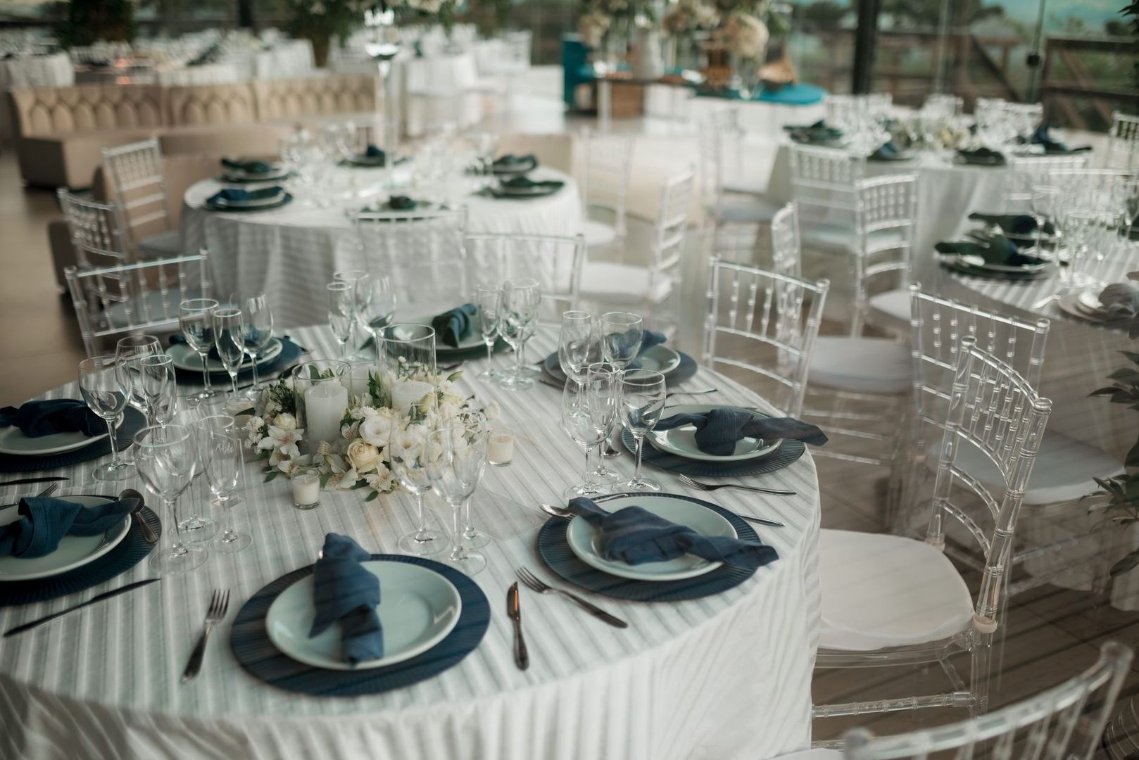 Festlokale med dækkede runde borde, glas, blomster og stole